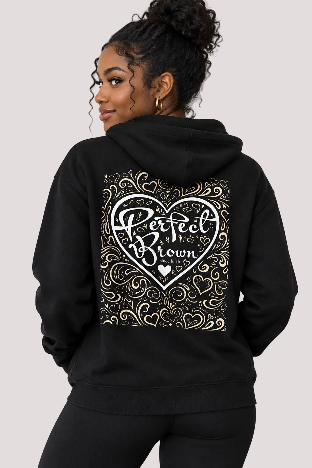 A woman shown from the back wearing a black hoodie with a large white graphic on the back. The graphic features a heart outline with the words 'Perfect For Brown' in stylized lettering, surrounded by ornate swirl patterns.