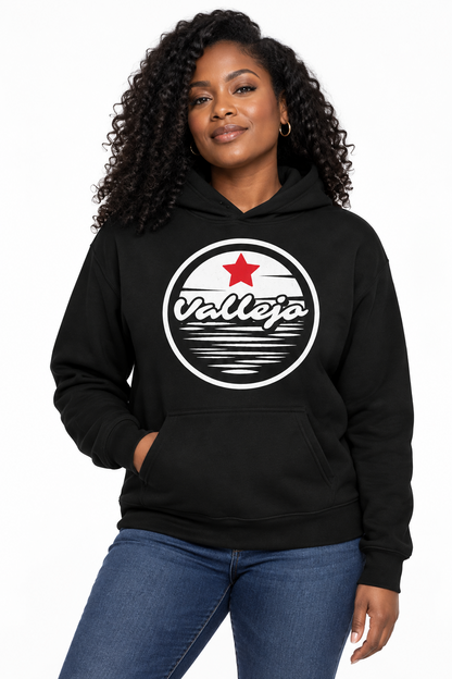 A woman wearing a black pullover hoodie with a circular 'Vallejo' graphic on the chest, paired with blue jeans, against a plain white background.